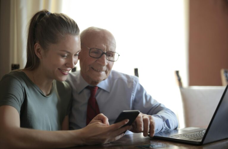 Hombre Mayor Y Mujer Joven Mirando un celular pagando la administración del conjunto